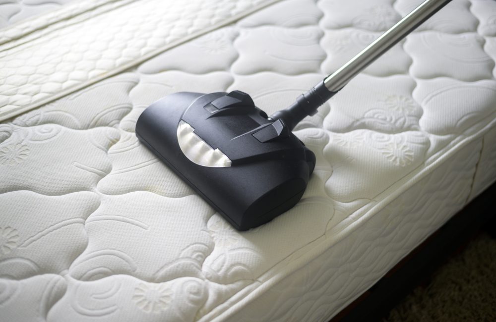 House cleaners is using dust mites remover machine in bed.